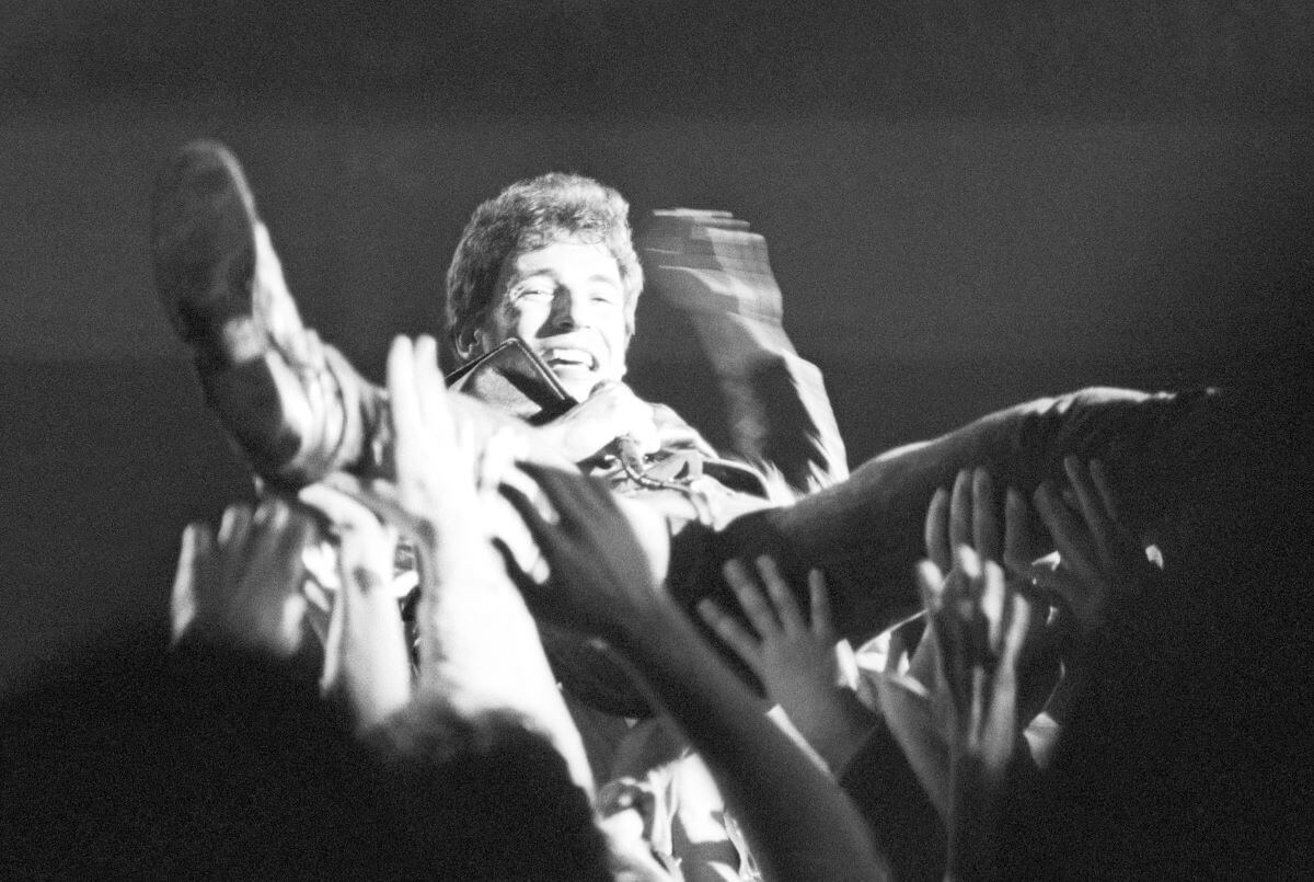 A black and white picture of Bruce Springsteen crowd surfing.