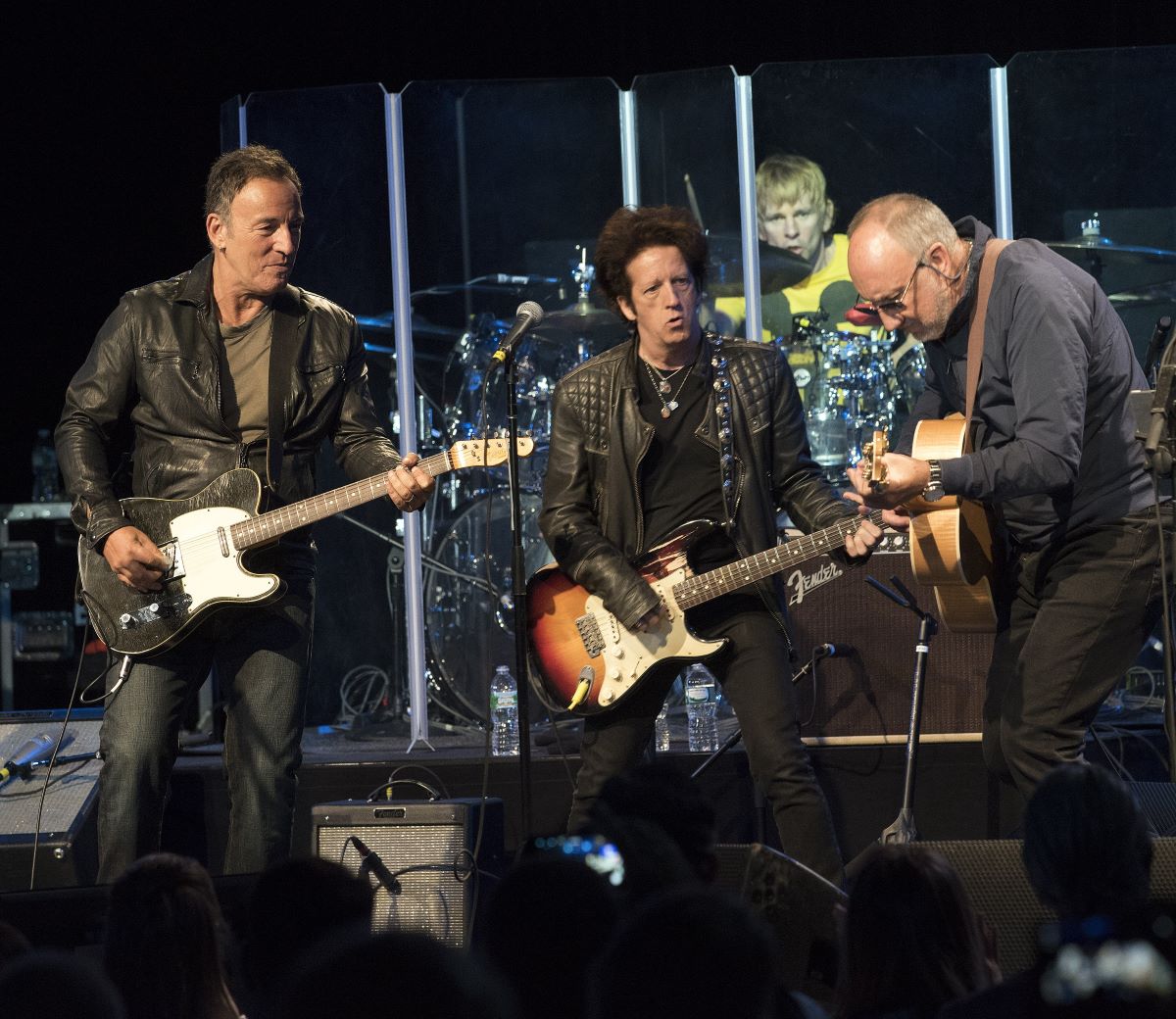 Bruce Springsteen plays guitar on a stage with Willie Nile and Pete Townshend.