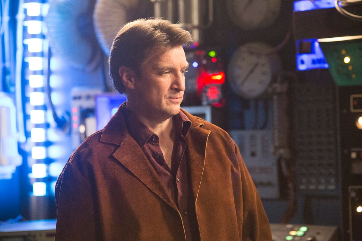 Nathan Fillion posing on a fictional 'Firefly' set on an episode of 'American Housewife'.