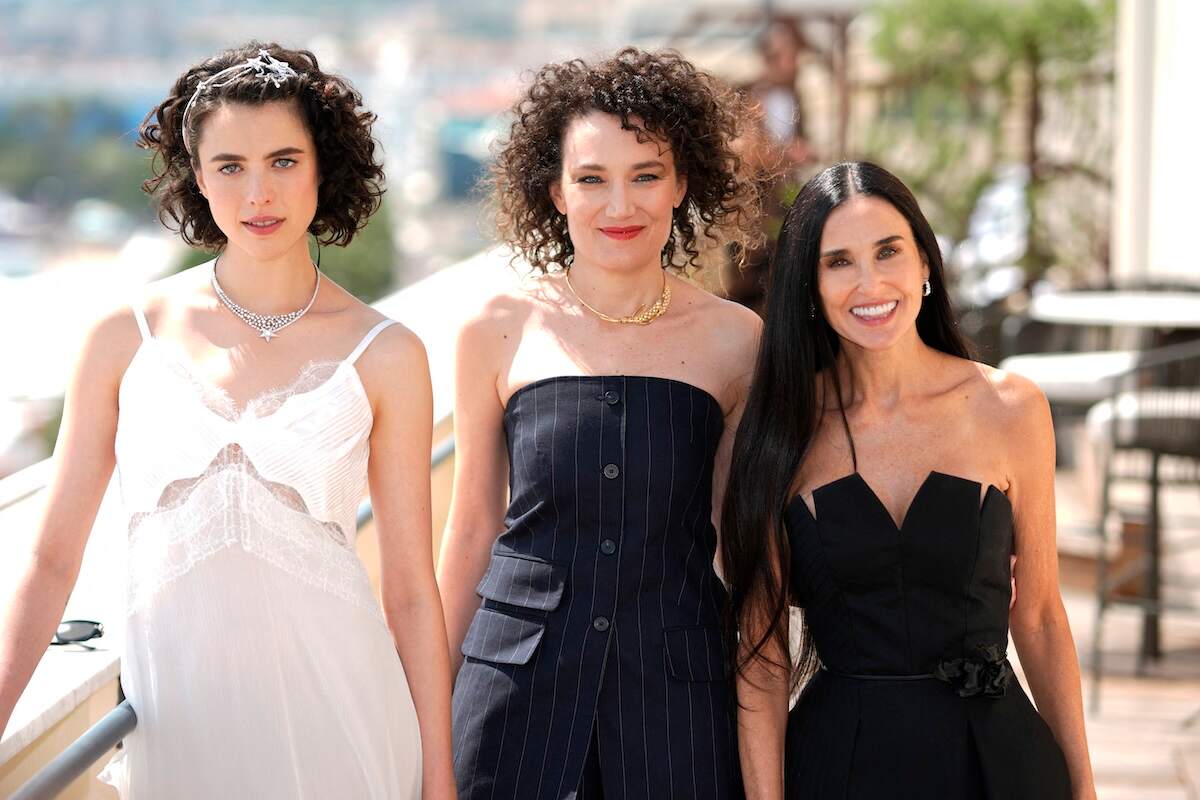 Actor Margaret Qualley, French director Coralie Fargeat, and Demi Moore pose on the balcony overlooking the French Riviera