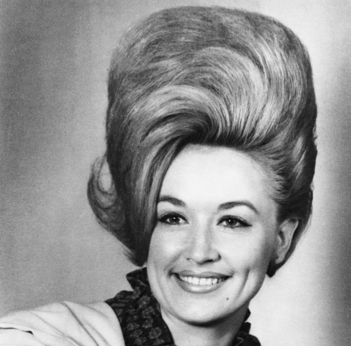 A black and white picture of Dolly Parton with her hair in a beehive.