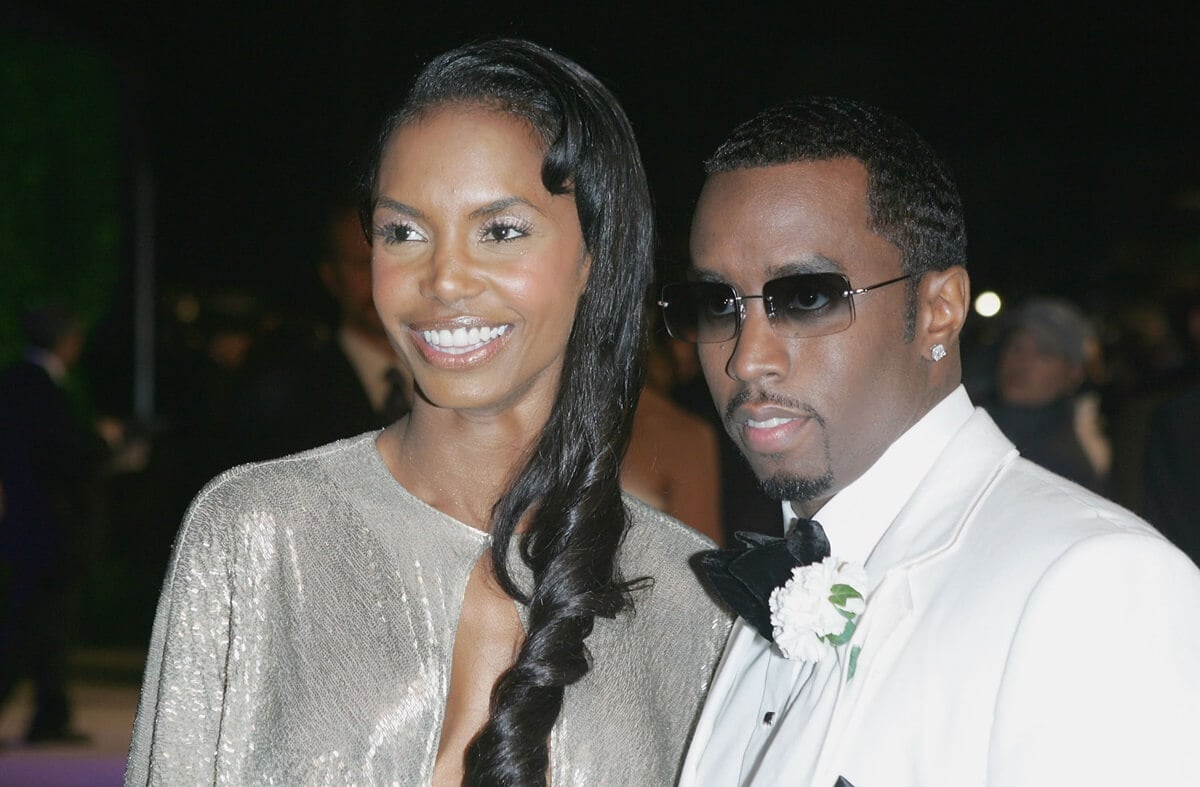 Diddy in a white suit posing next to Kim Porter at the Vanity Fair Oscar Party.