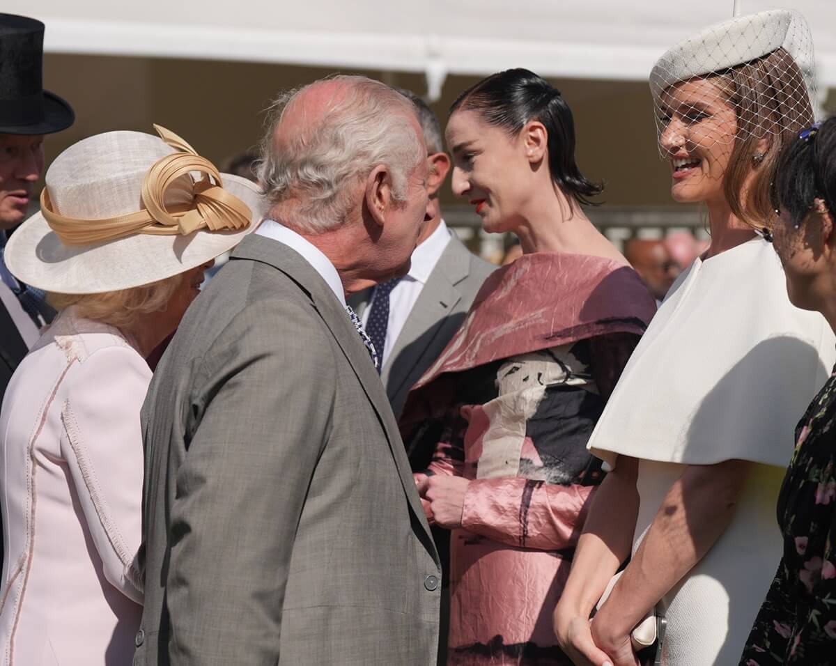 King Charles III and Queen Camilla speak with Rosie Huntington-Whiteley (all-white outfit) at The Creative Industries Garden Party at Buckingham Palace