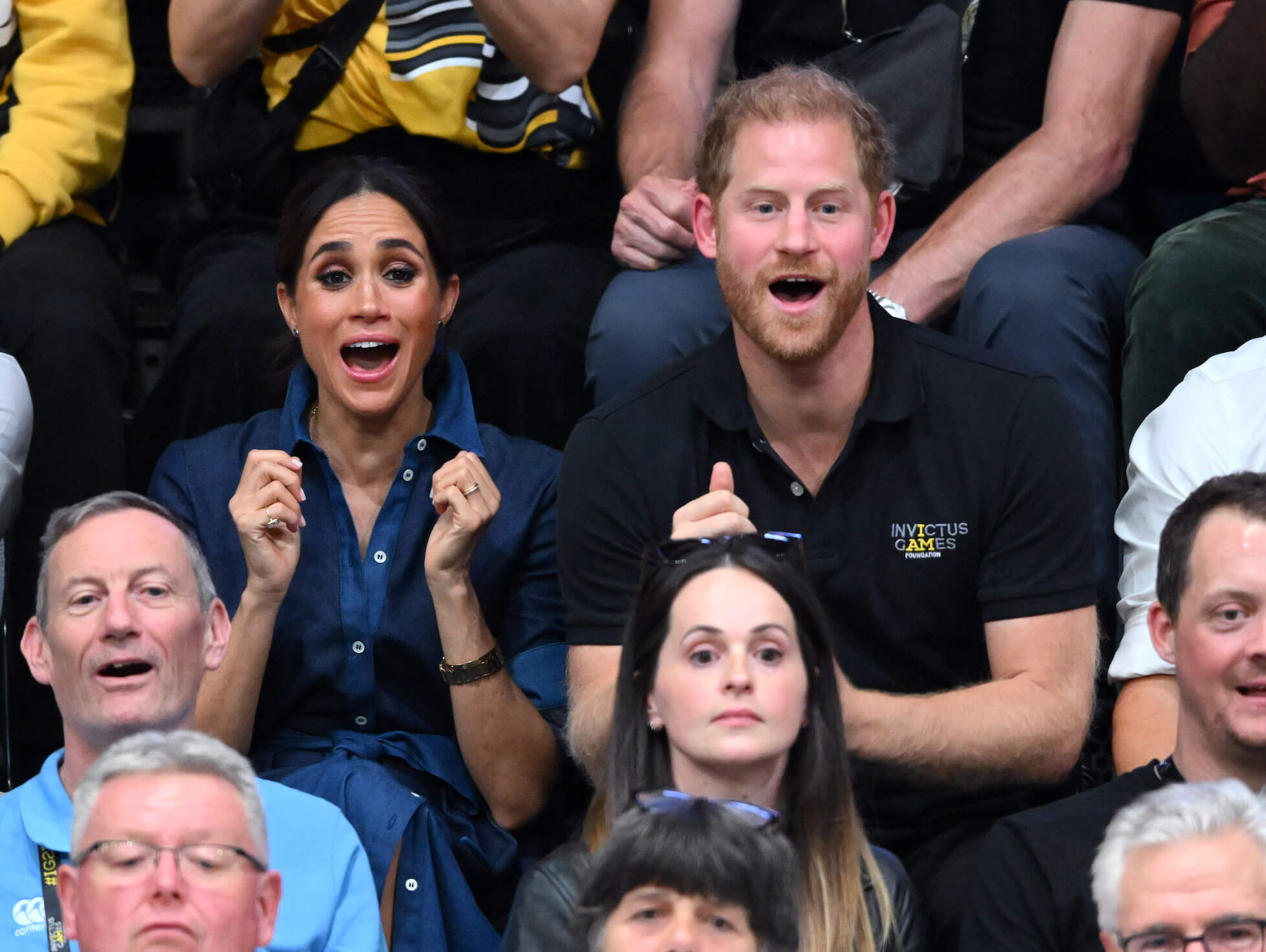 Meghan and Prince Harry cheering in a crowd at the Invictus Games in 2023