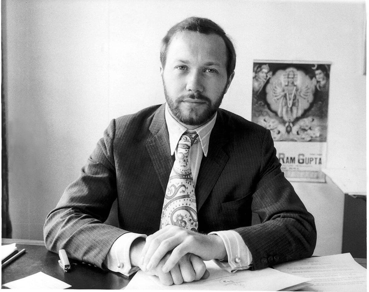 A black and white picture of Peter Brown wearing a suit and sitting at a desk.