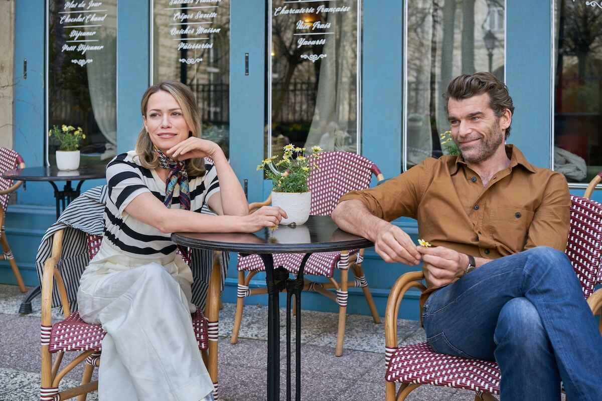 A man and a woman sitting outside at a Parisian cafe table