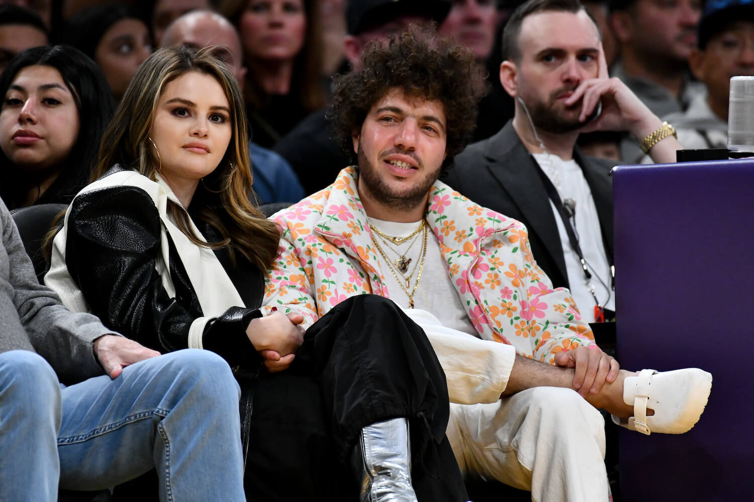Selena Gomez and Benny Blanco sitting next to each other at a basketball game in 2024