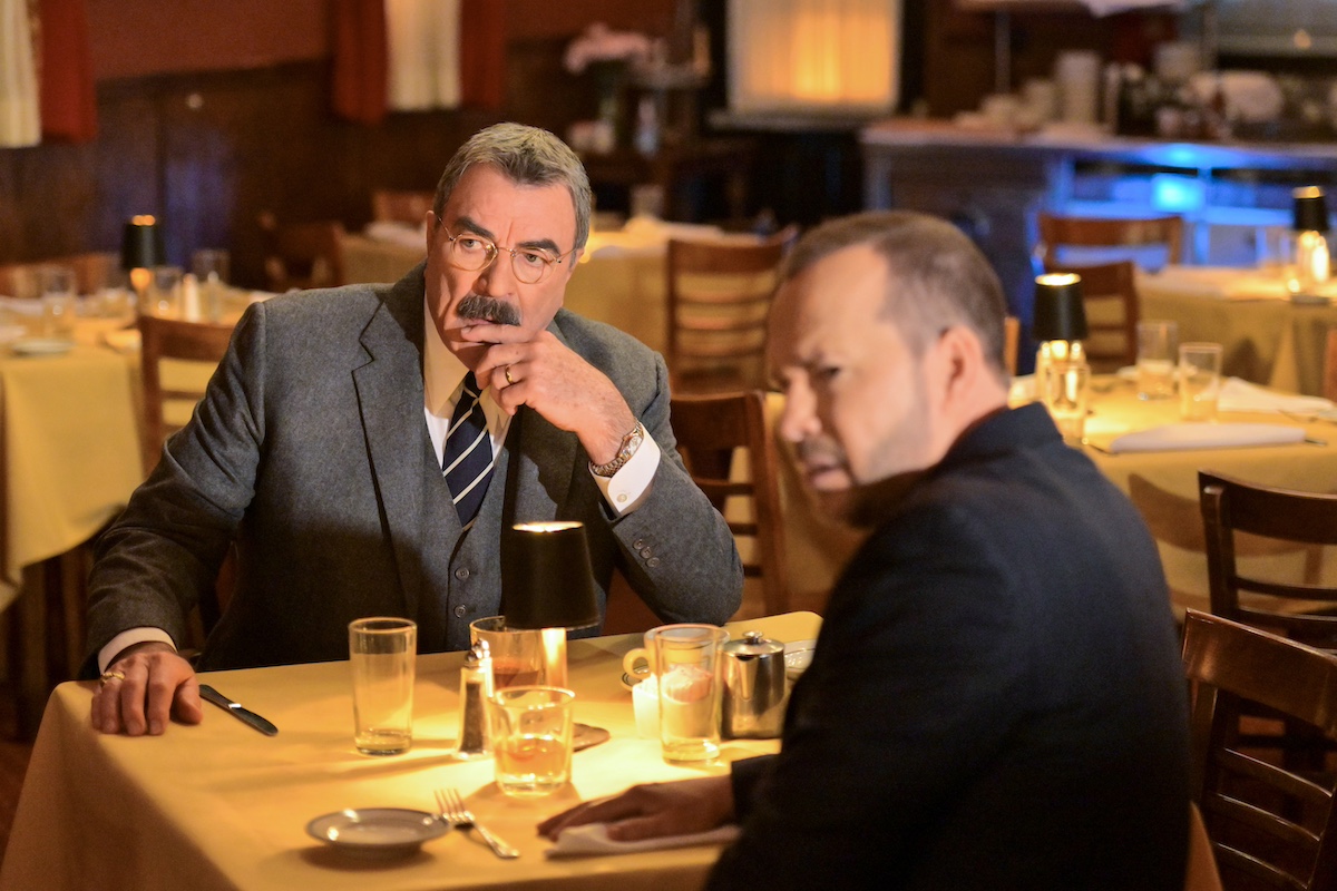 Tom Selleck and Donnie Wahlberg sitting a table in a restaurant in 'Blue Bloods'