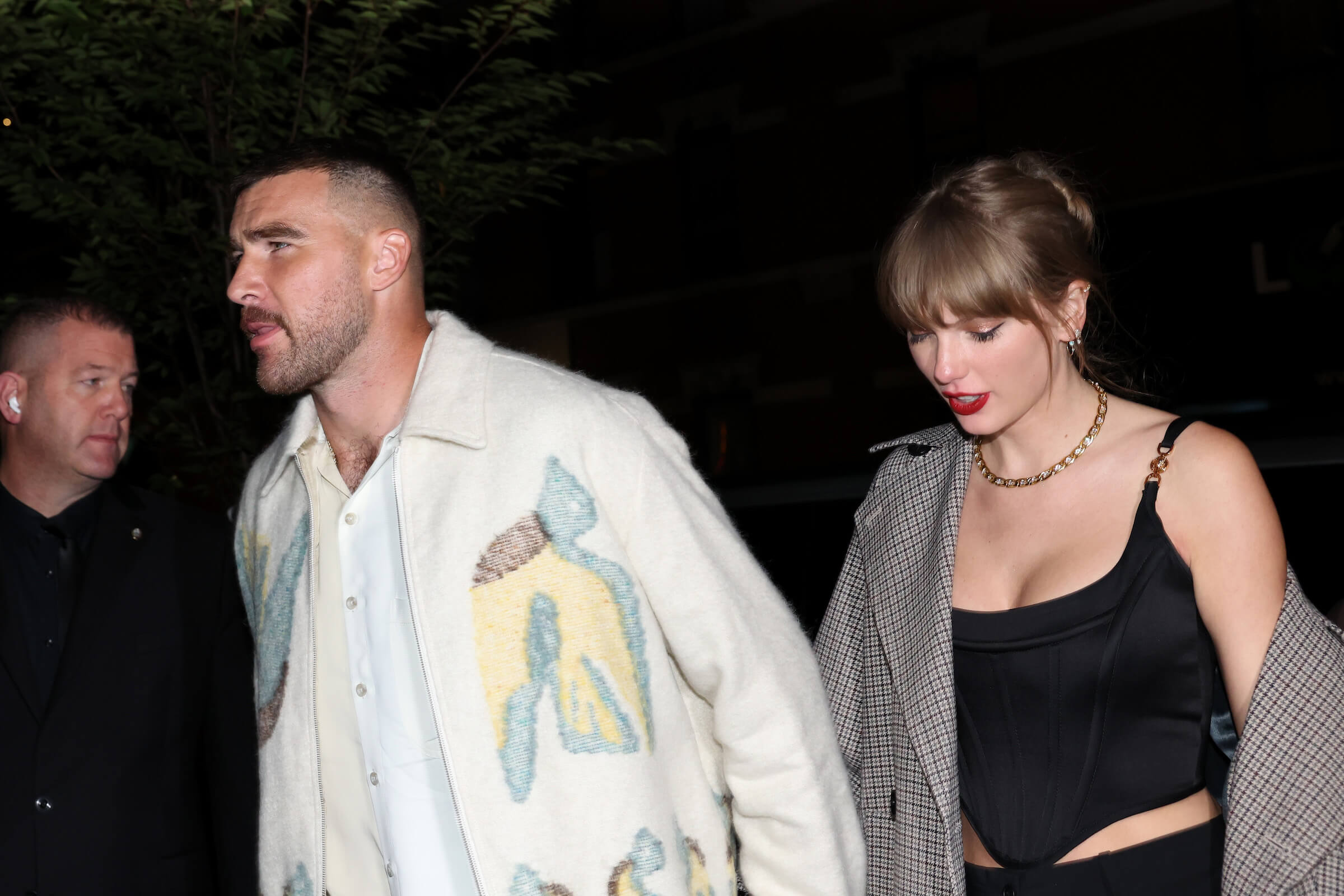 Travis Kelce and Taylor Swift walking hand-in-hand at night