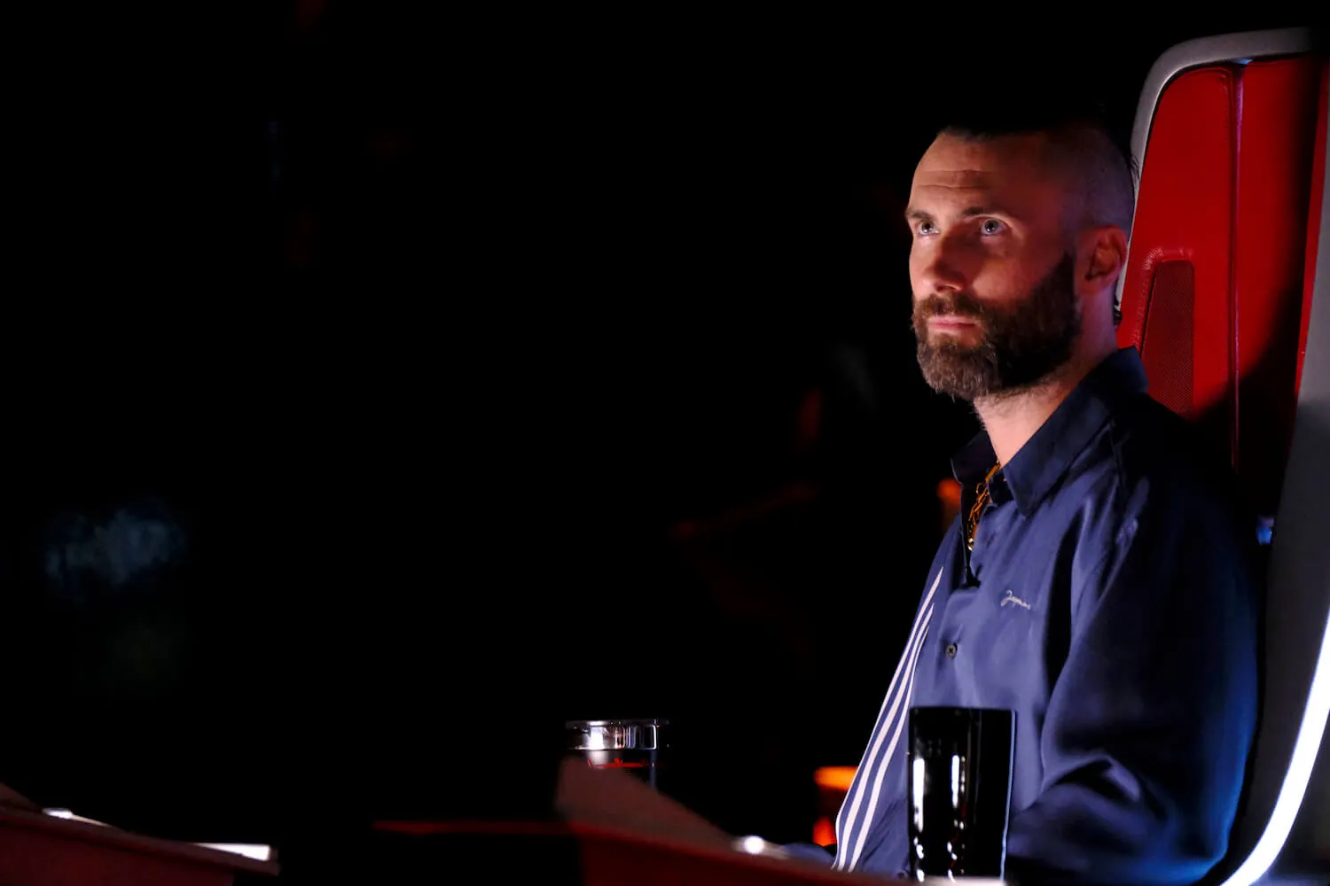 Adam Levine sitting in a red chair in 'The Voice' Season 16