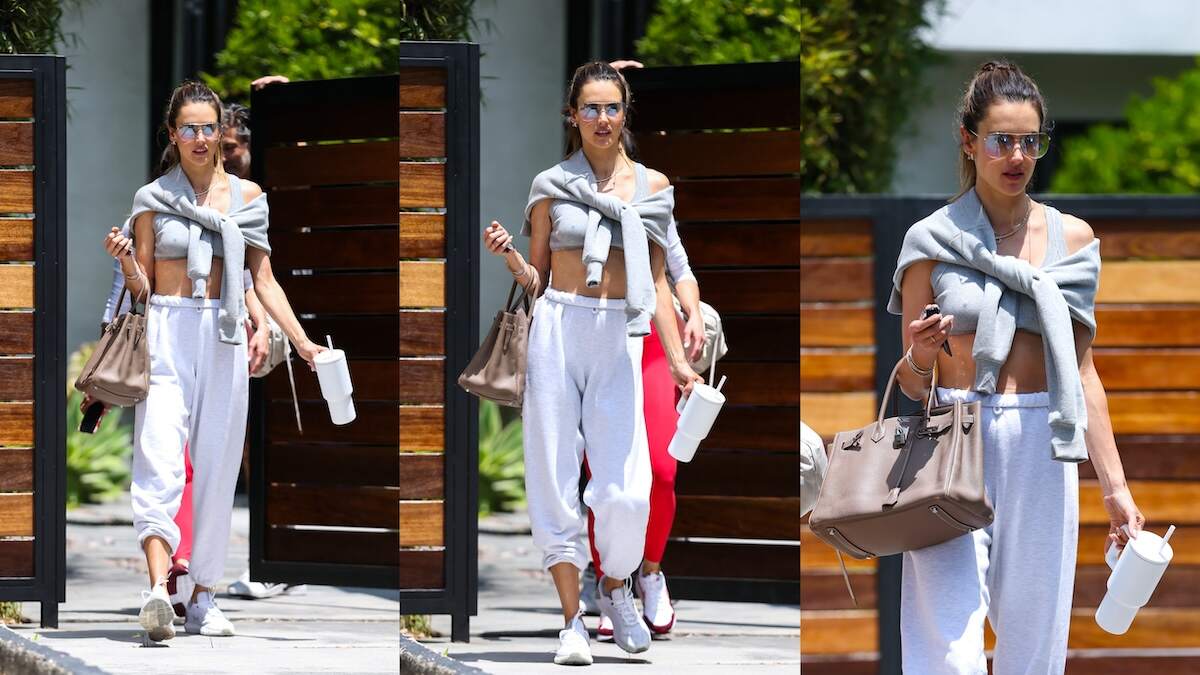 Model Alessandra Ambrosio leaves a workout in LA wearing gray sweatpants and a gray sports bra, carrying a white tumbler