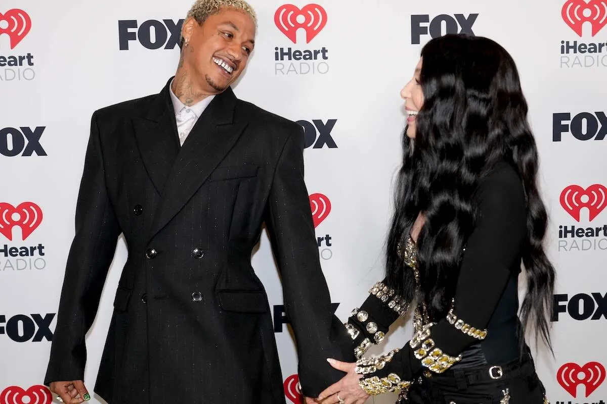 Couple Alexander Edwards and Cher laugh together on the red carpet at an iHeart Radio event