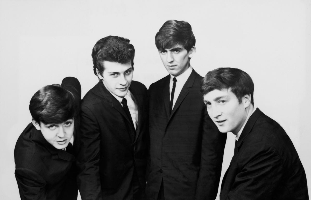 A black and white picture of Paul McCartney, Pete Best, George Harrison, and John Lennon wearing suits and posing together.