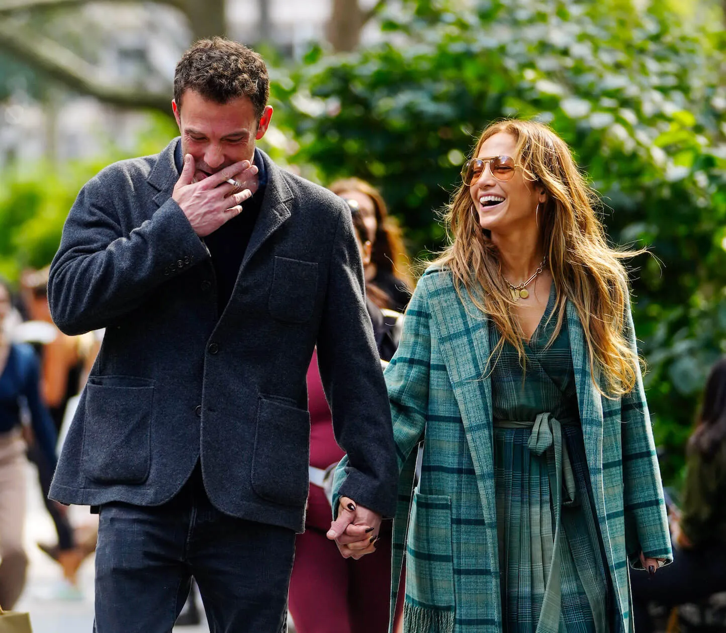 Ben Affleck smoking a cigarette and walking with Jennifer Lopez, who's laughing