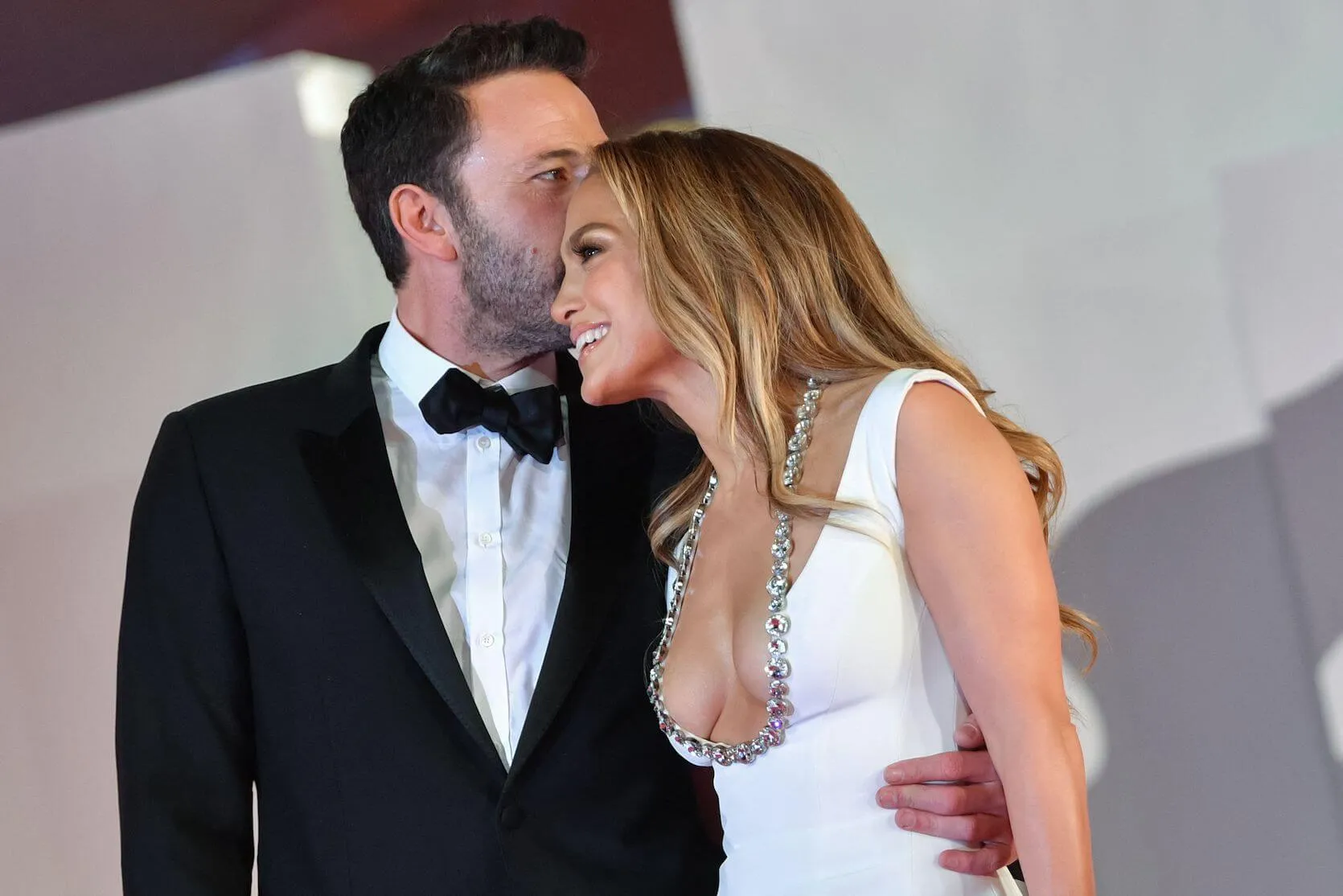 Ben Affleck kissing Jennifer Lopez on the side of the head as she smiles and leans into him at a 2021 movie premiere