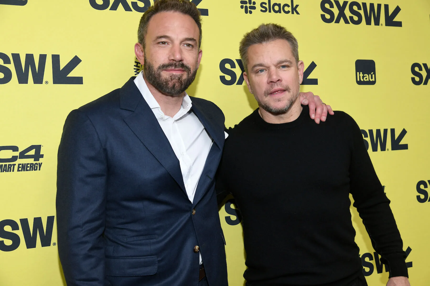 Ben Affleck with his arm around Matt Damon's shoulders against a yellow SXSW backdrop in 2023