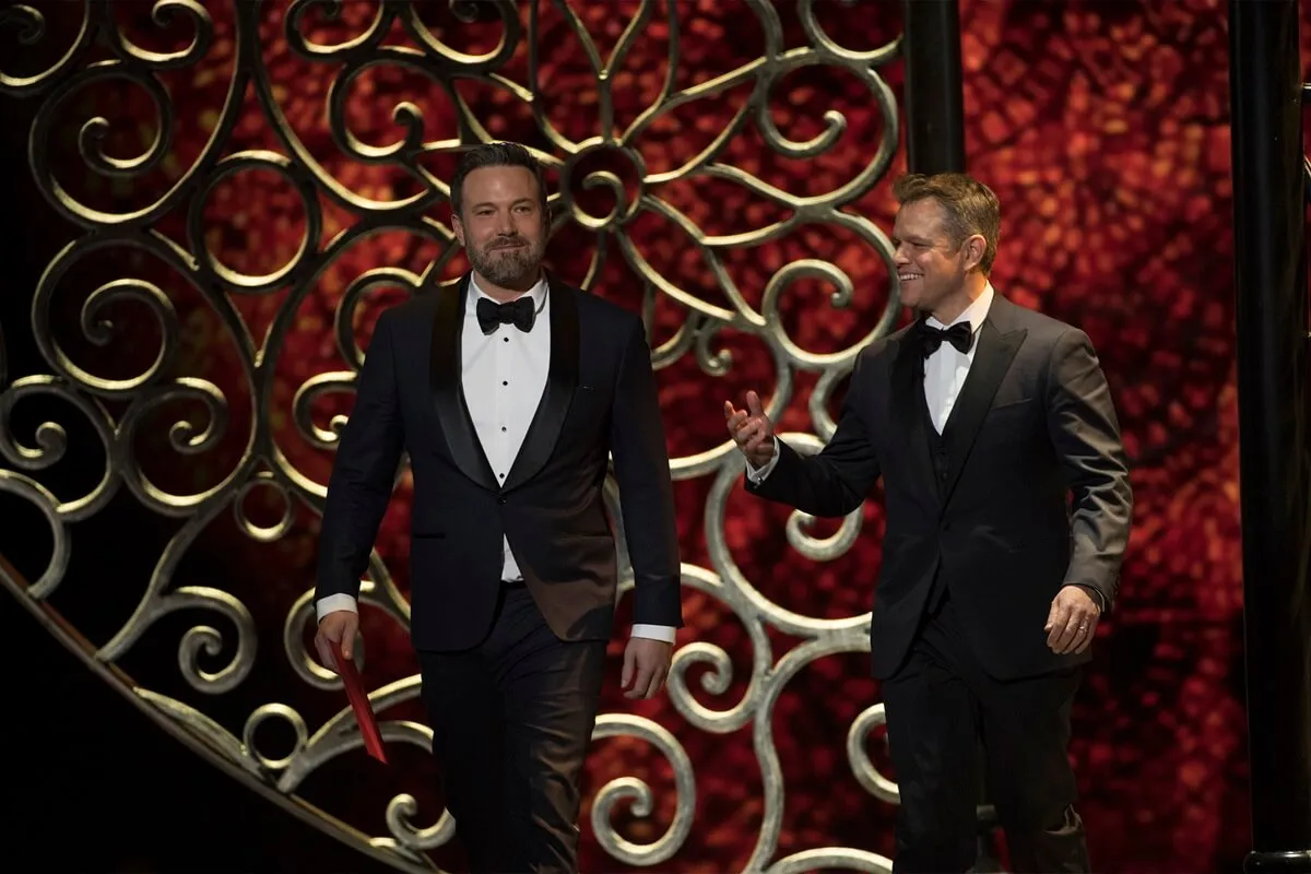 Ben Affleck and Matt Damon about to present at the Oscars while wearing suits.