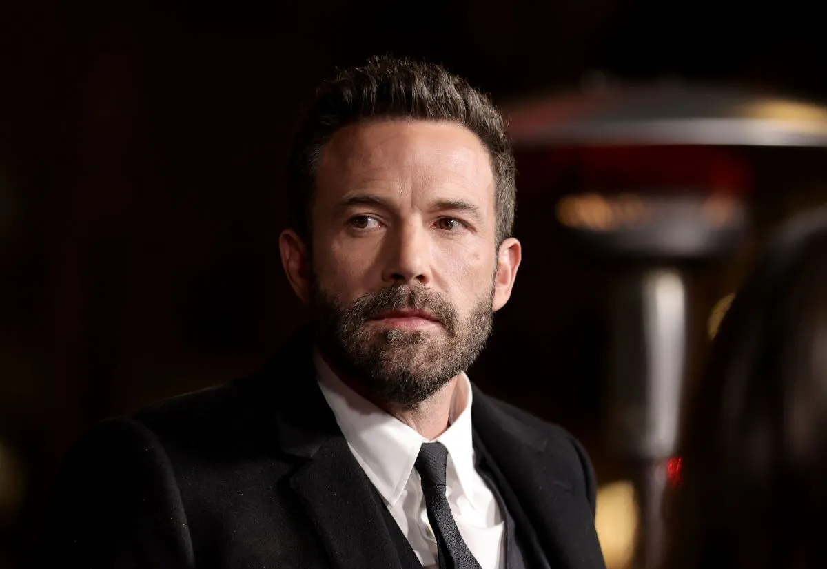 Ben Affleck wears a suit and tie and sits in a theater.