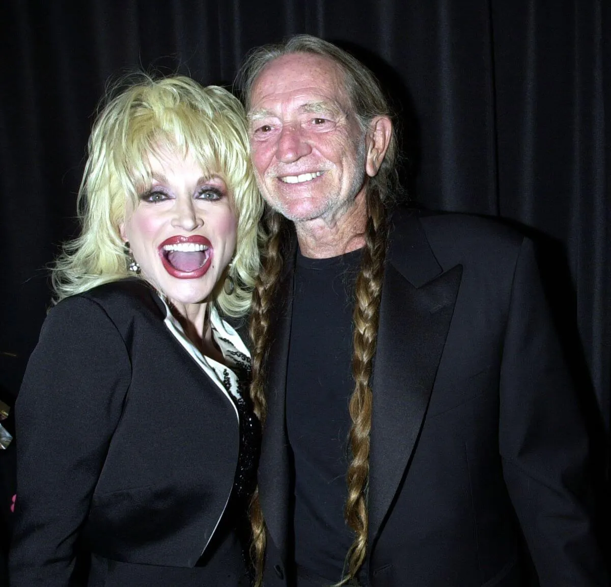 Dolly Parton and Willie Nelson wear black and smile together.