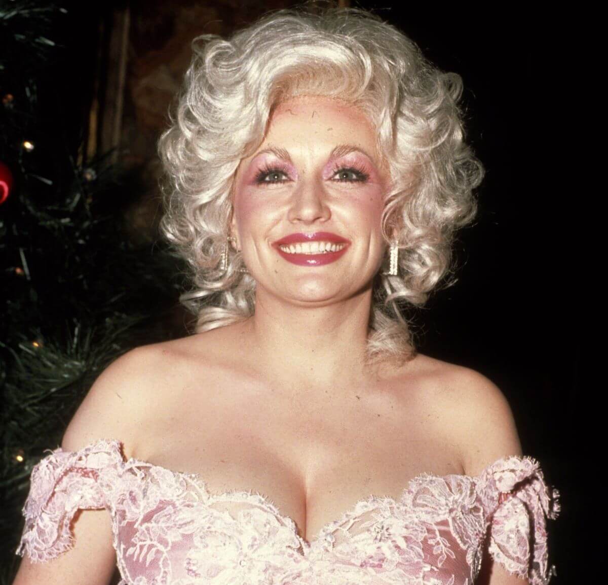 Dolly Parton wears a pink dress. She smiles.