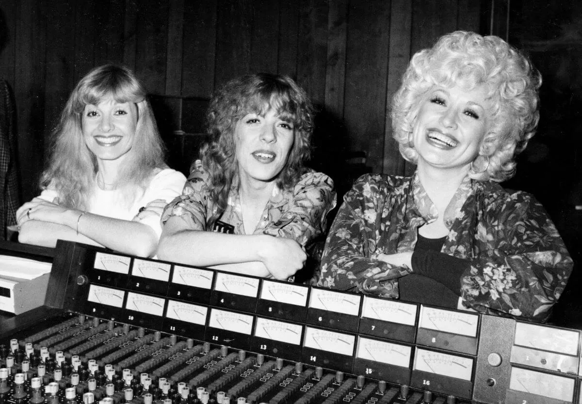 A black and white picture of Stella, Frieda, and Dolly Parton standing behind a recording control panel.