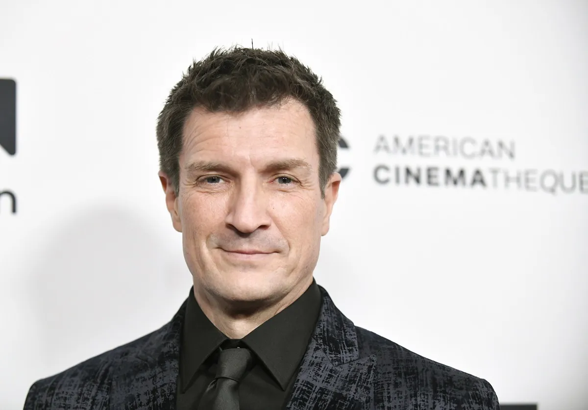 Nathan Fillion posing in a black suit at the 36th Annual American Cinematheque Award Ceremony.