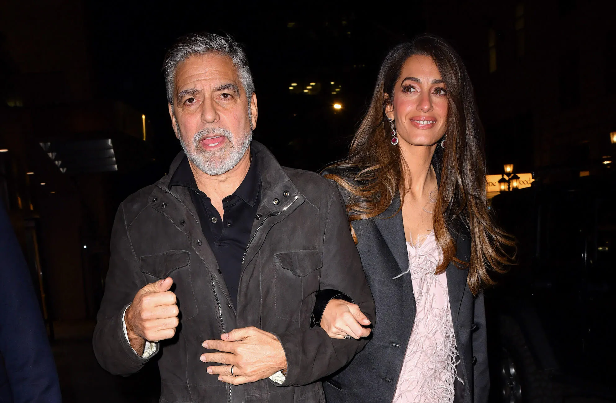 George and Amal Clooney walking outside at night arm in arm in 2023