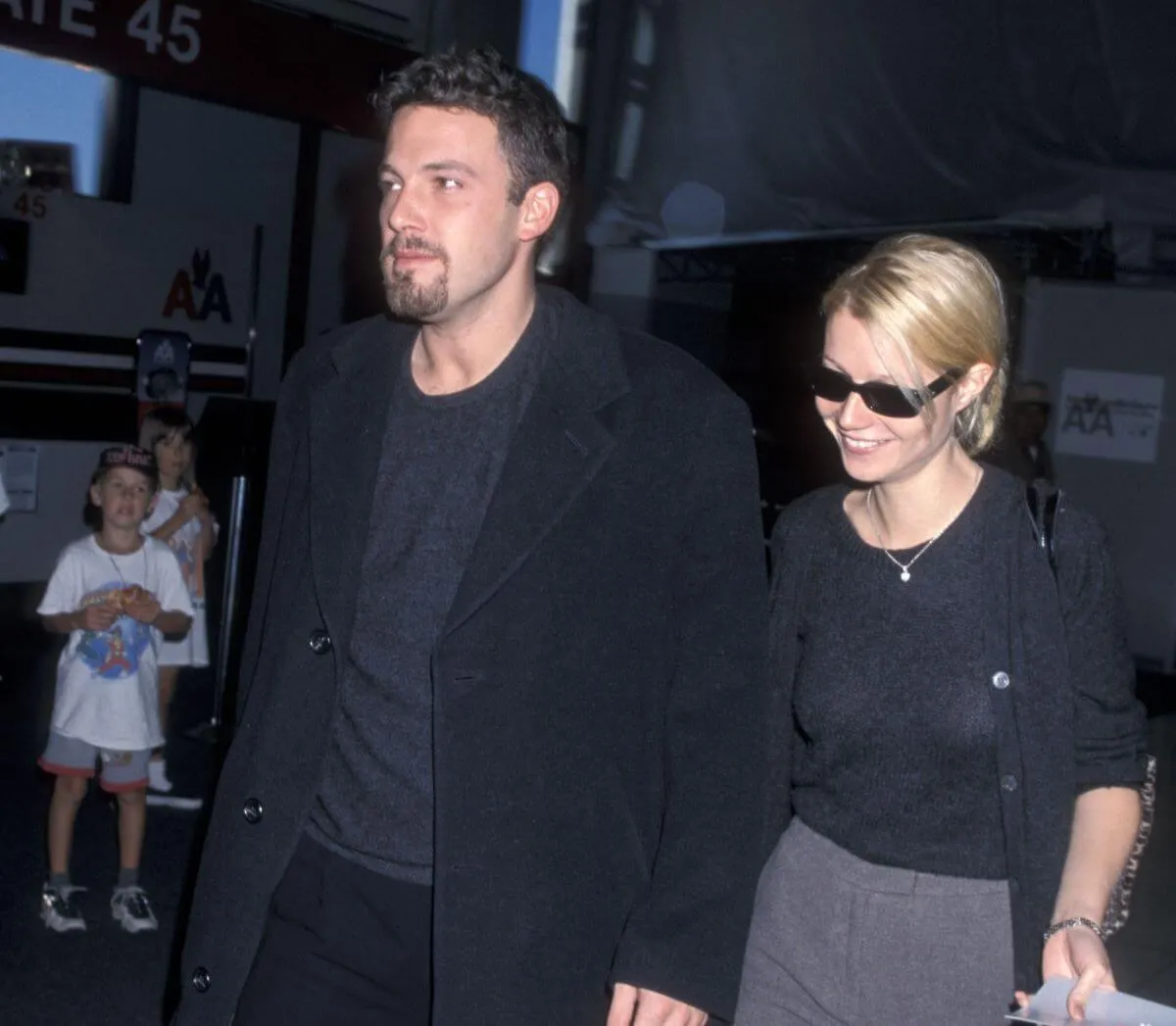 Ben Affleck and Gwyneth Paltrow hold hands and walk together. They both wear black and she wears sunglasses.