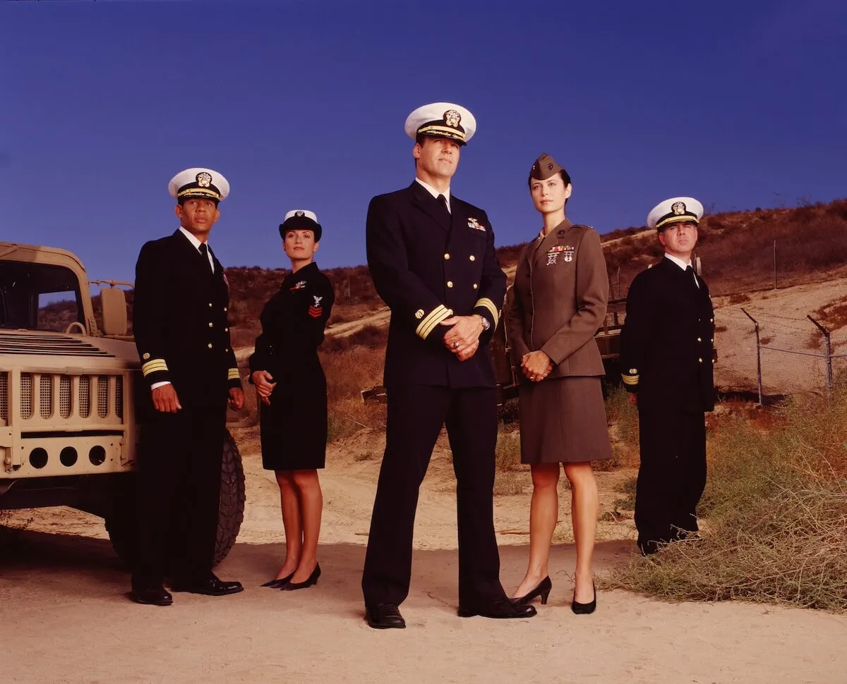 The cast of 'JAG' in military uniforms standing in the desert