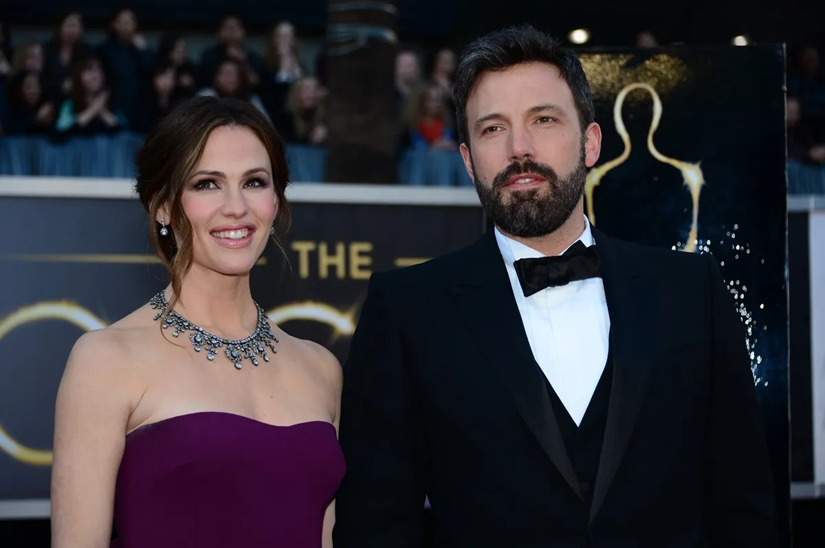 Ben Affleck and Jennifer Garner arriving on the red carpet for the 85th Annual Academy Awards. Garner is wearing a purple strapless dress and Affleck is wearing a black suit with a bow tie. 