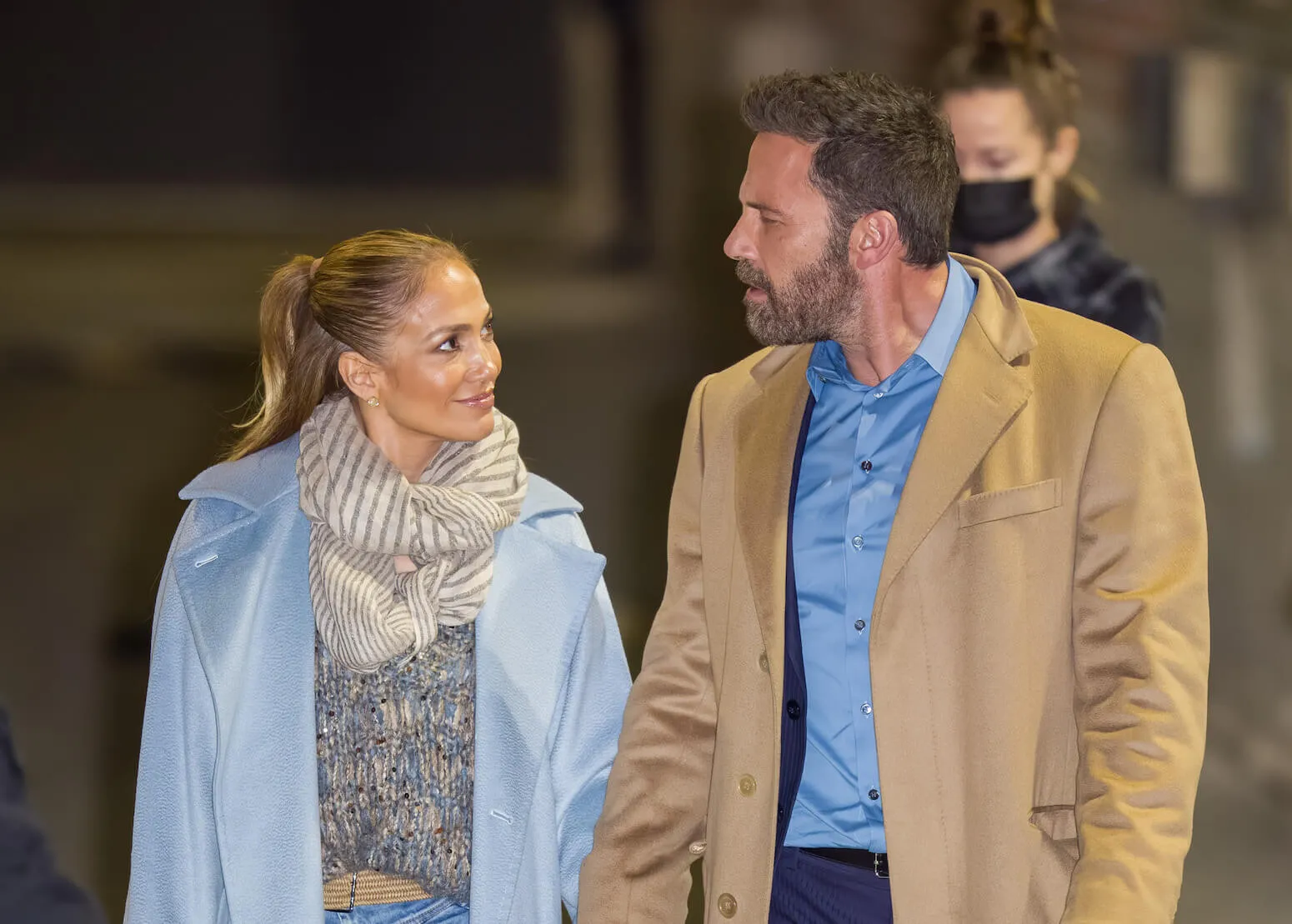 Jennifer Lopez and Ben Affleck walking and looking at each other in 2021. They are dressed for cold weather.