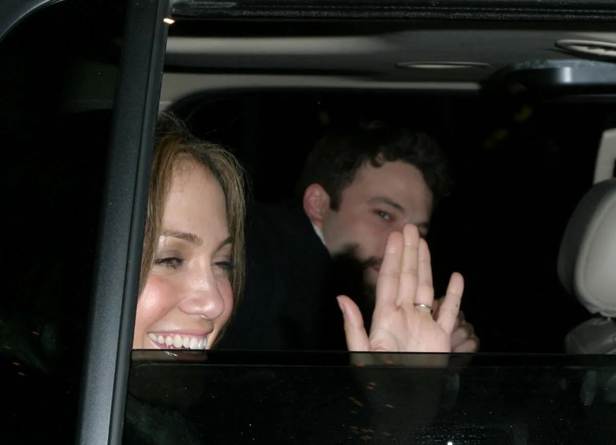 Jennifer Lopez waves from the window of a car. Ben Affleck sits next to her.