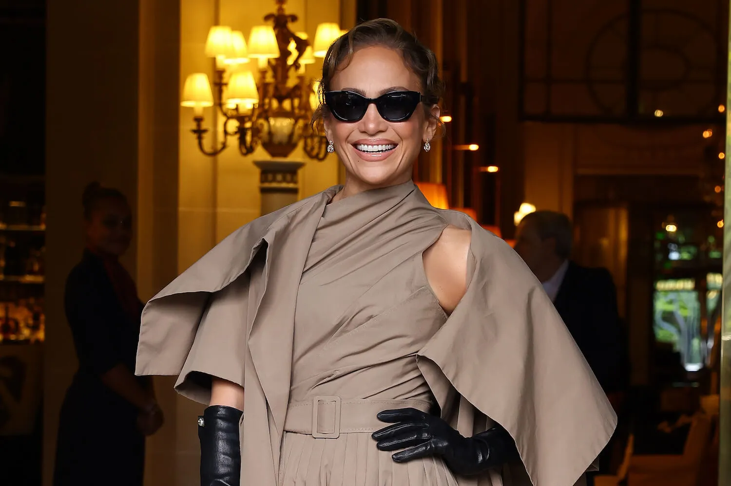 Jennifer Lopez smiling in a tan Dior outfit while at the Christian Dior Haute Couture Fall/Winter 2024-2025 show as part of Paris Fashion Week