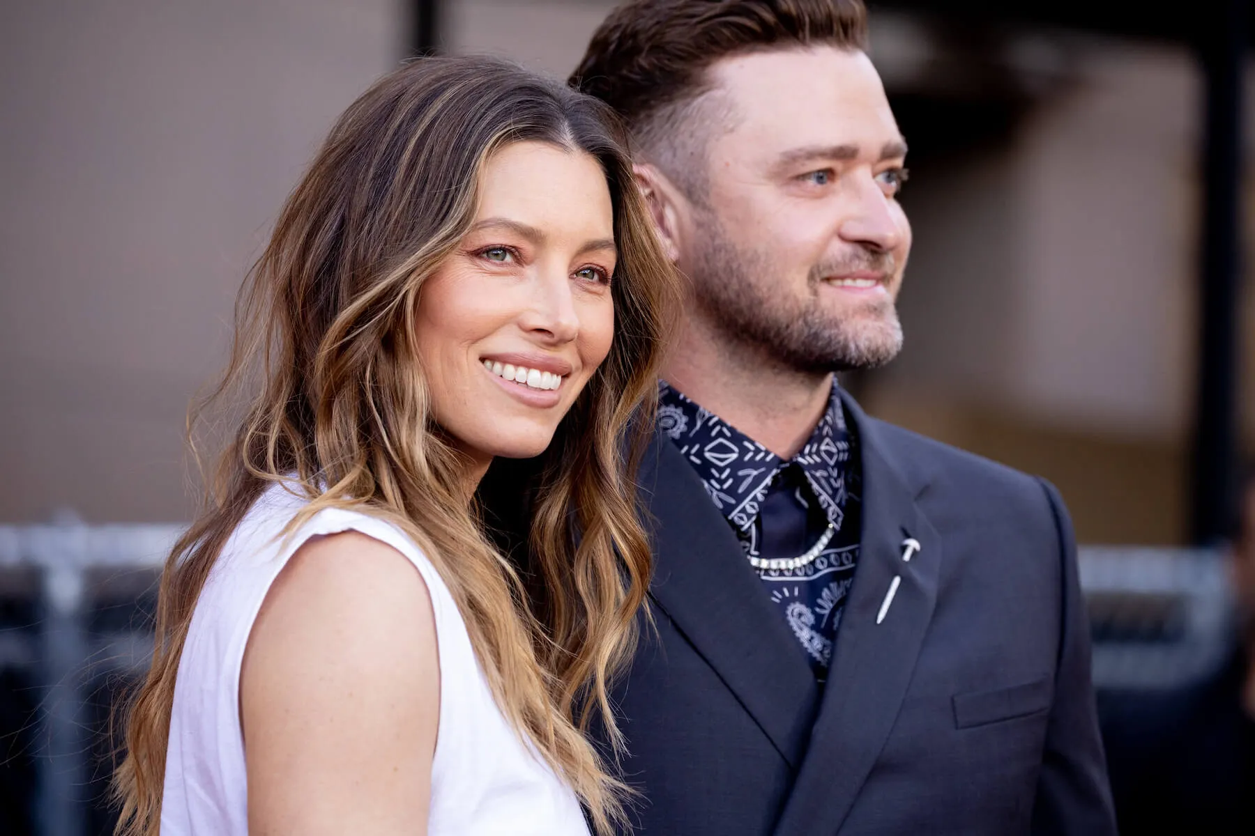 Jessica Biel smiling at a movie premiere in 2022 with Justin Timberlake slightly out of focus to her side