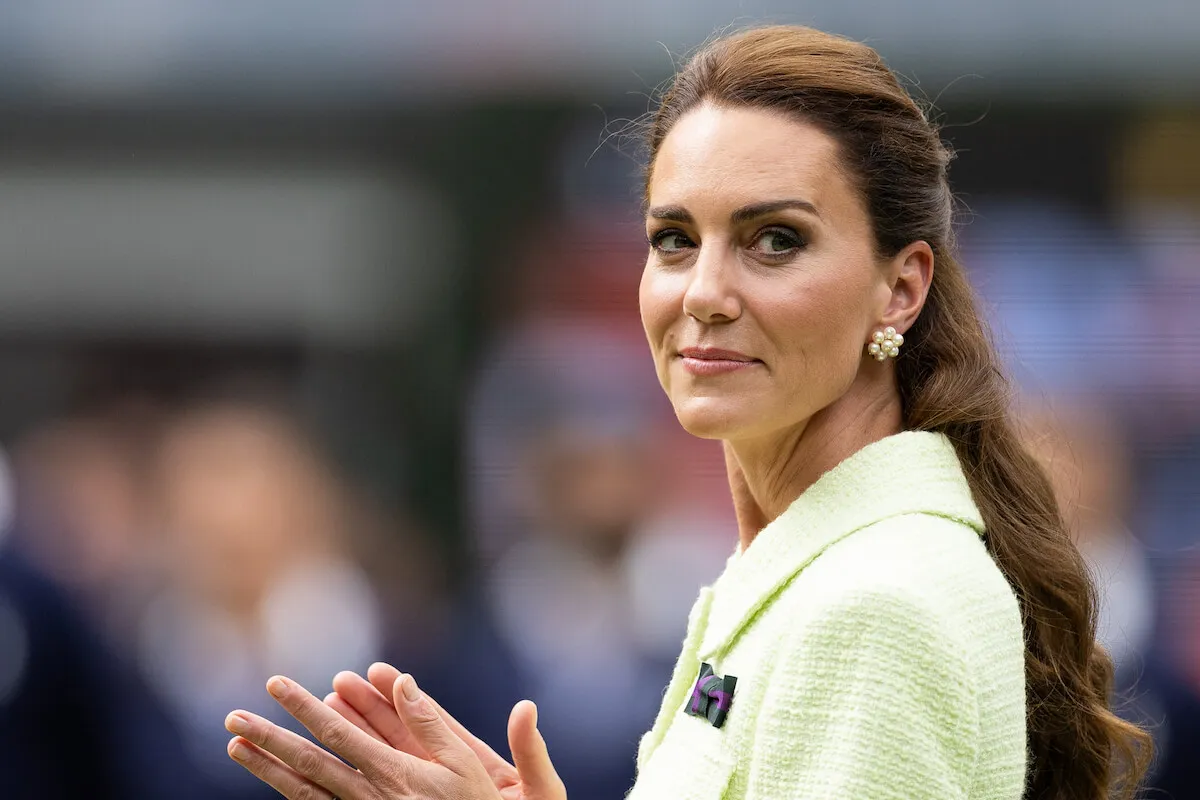 Kate Middleton, who the Wimbledon chair is 'hopeful' will attend the tennis tournament, claps wearing a green blazer.