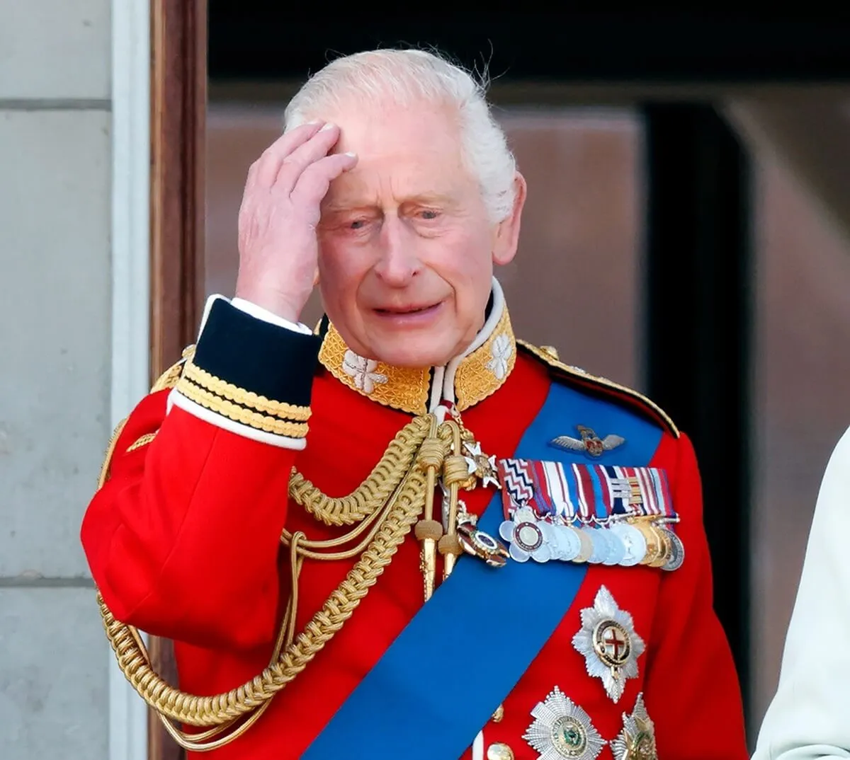 King Charles III, wearing his Irish Guards uniform, standing on the balcony of Buckingham Palace after attending Trooping the Colour