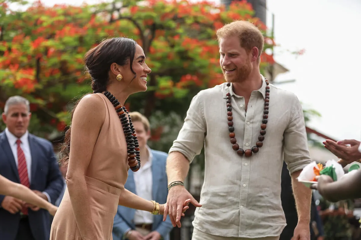 Meghan Markle and Prince Harry, who are 'moving on' from royal family drama at different speeds, hold hands in Nigeria