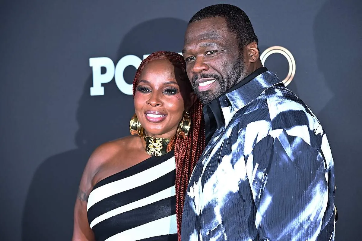 Wearing a black and white striped dress, Mary J. Blige stands with 50 Cent on the red carpet