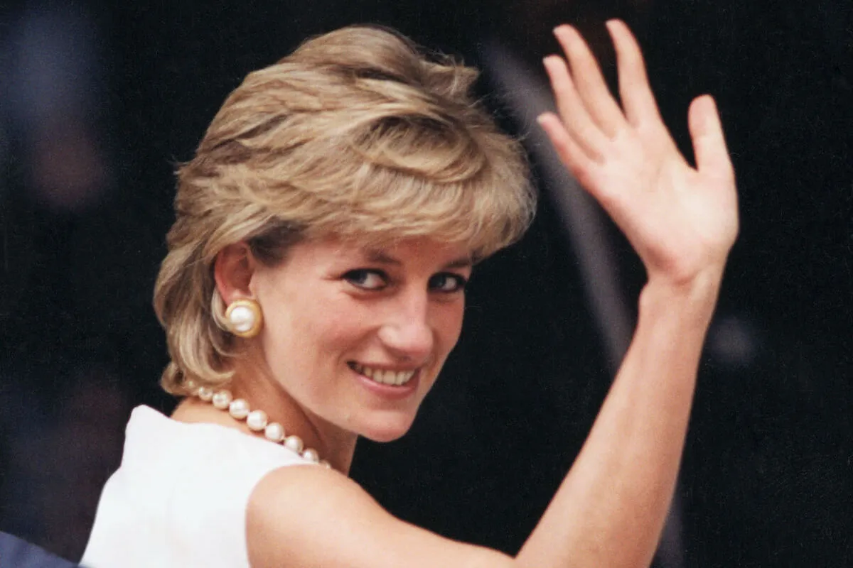 Princess Diana, whom Kevin Costner wanted to star in a sequel to 'Bodyguard,' waves wearing a white dress and pearl jewelry. 