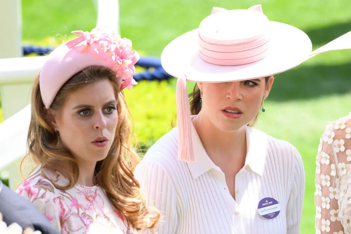 Princesses Beatrice and Eugenie, who Prince Andrew may get involved wiht the Royal Lodge dispute, stand next to each other and look on