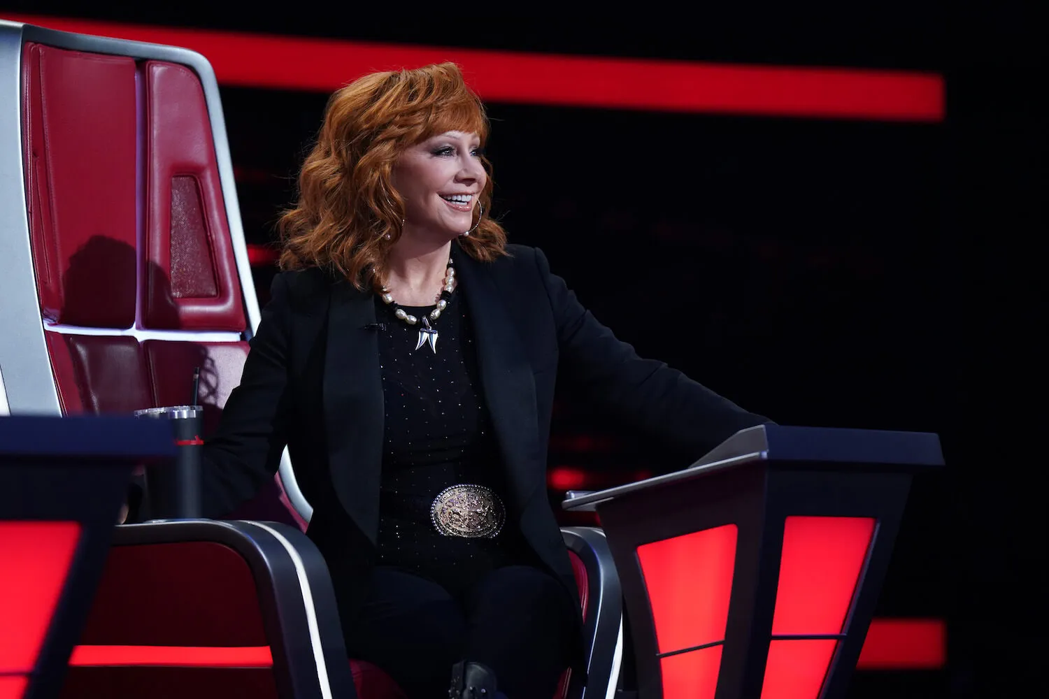 Reba McEntire standing and smiling on 'The Voice' Season 25 set