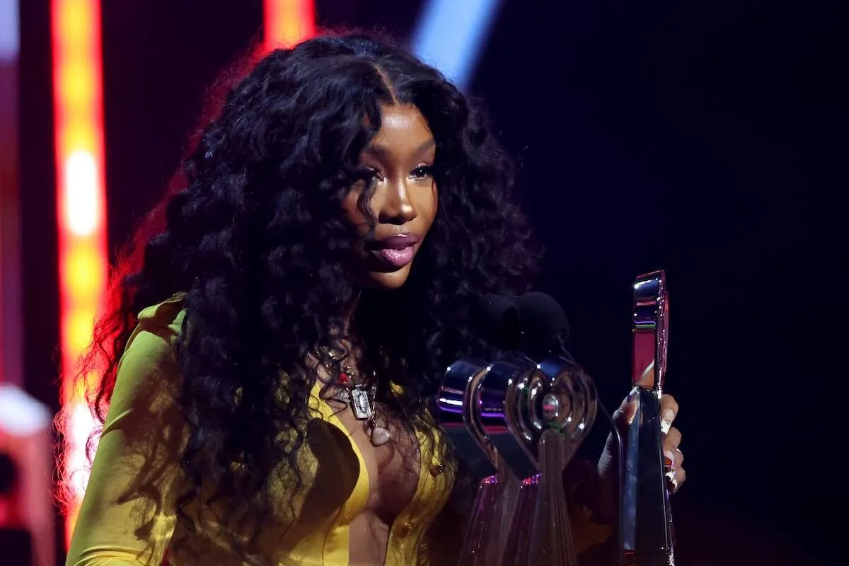 Wearing a yellow dress, SZA accepts the R&B Artist of the Year award onstage during the 2024 iHeartRadio Music Awards