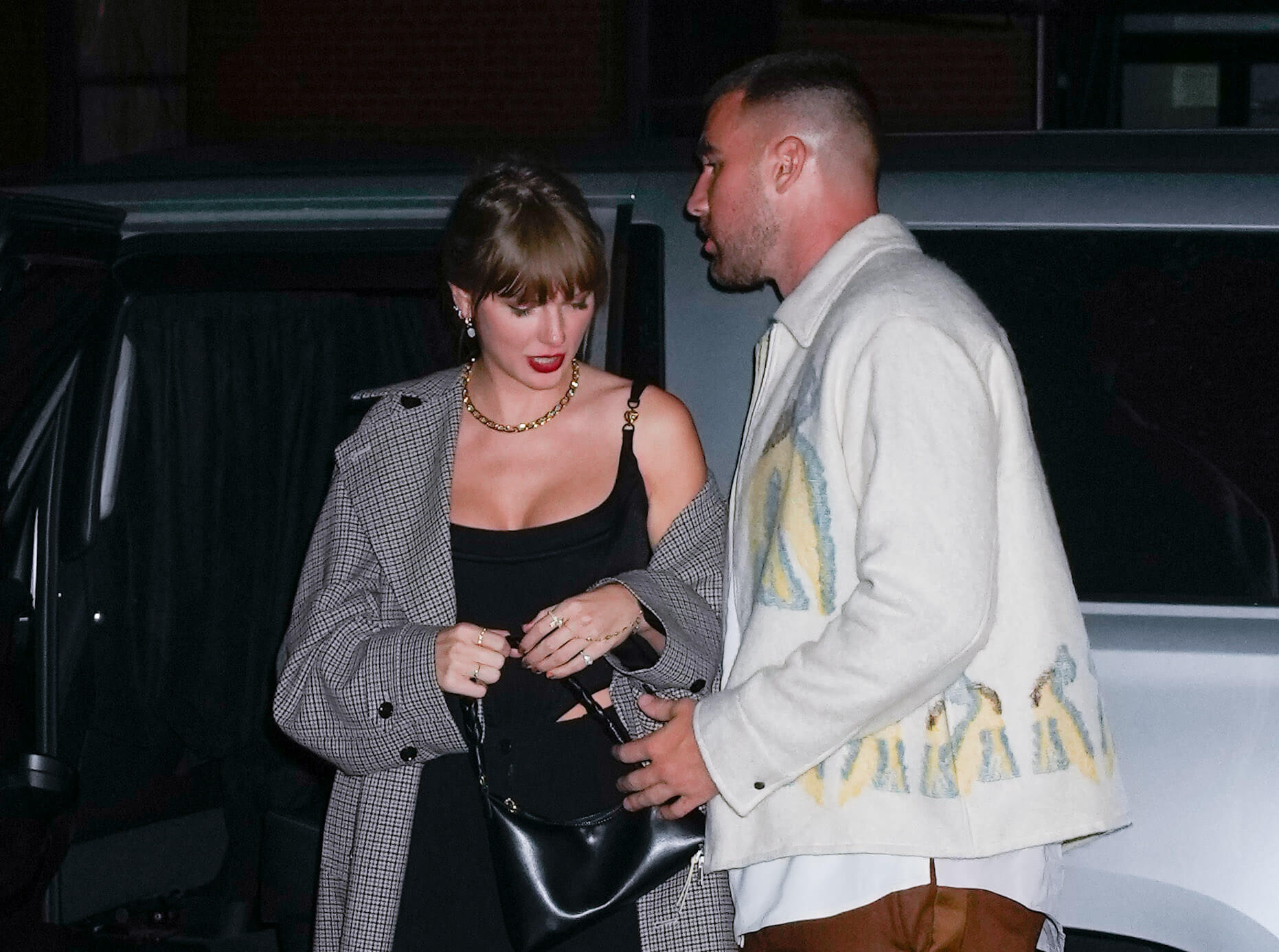 Taylor Swift stepping out of a car with Travis Kelce at night in October 2023