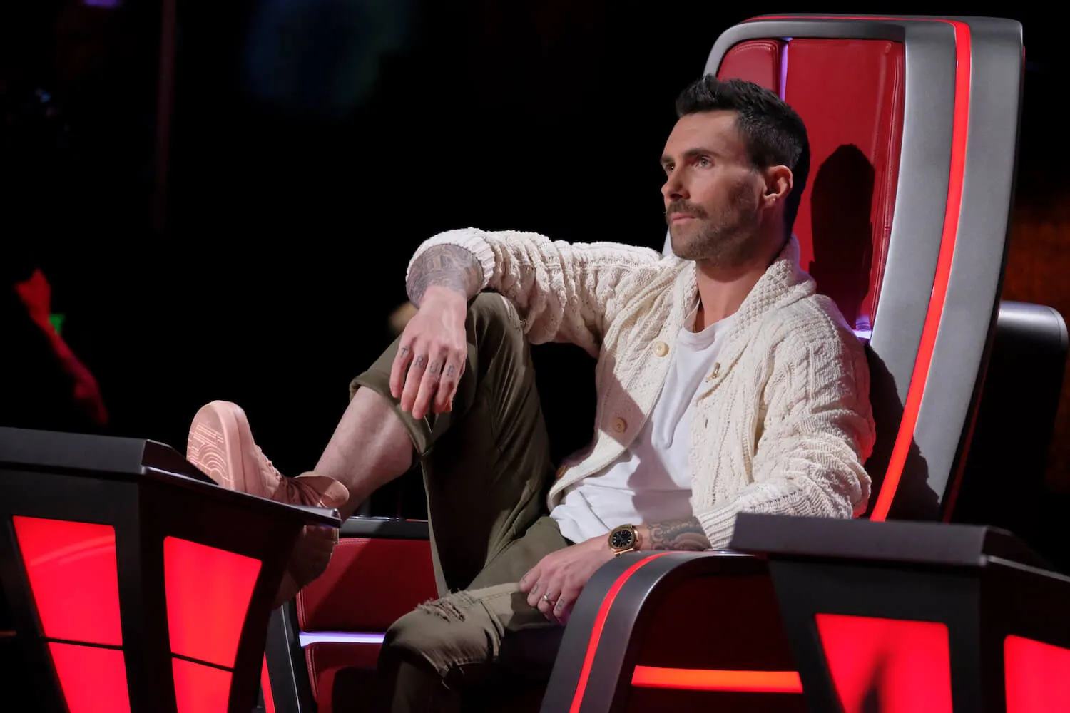 'The Voice' coach Adam Levine sitting in the red coaching chair with his leg up
