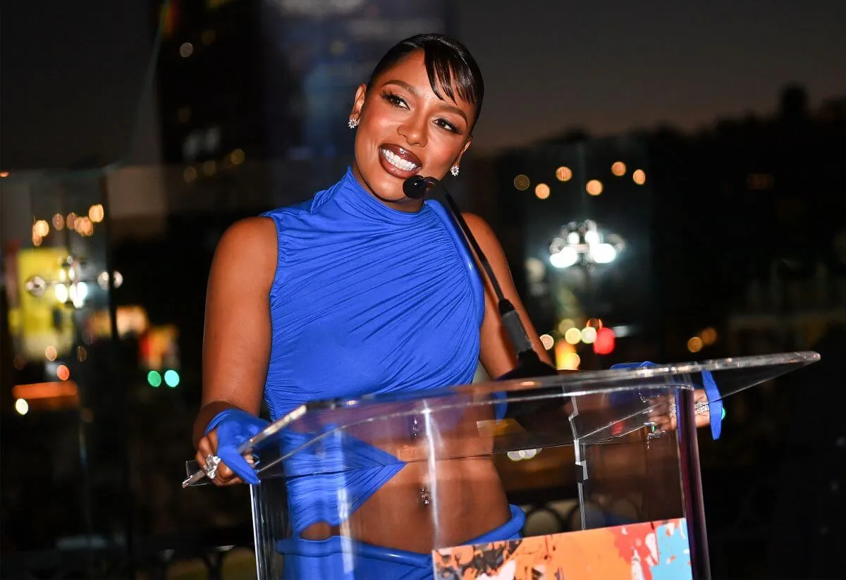 Victoria Monet wears a blue dress and stands at a podium at the ASCAP awards.