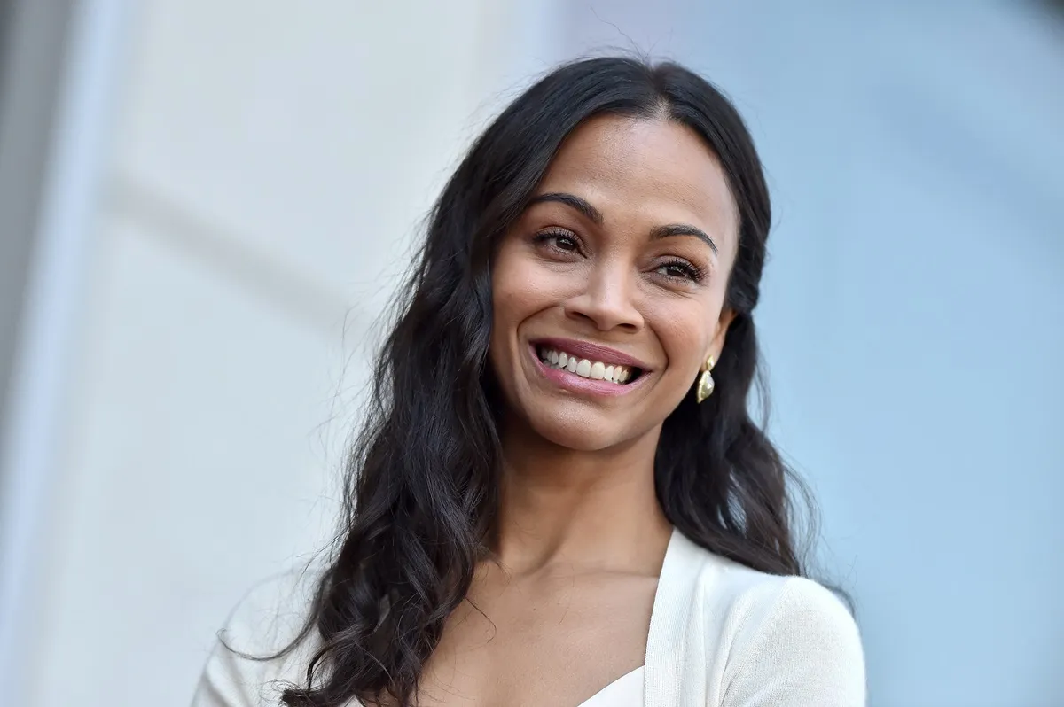 Zoe Saldana posing in a white dress at the Hollywood Walk of Fame.