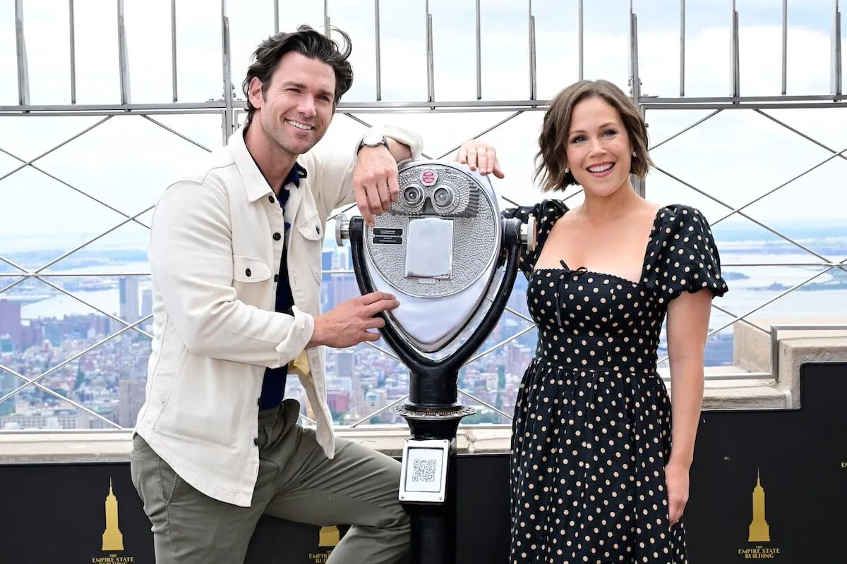 Kevin McGarry and Erin Krakow posing with a scenic viewer on the Empire State Building outdoor observation deck