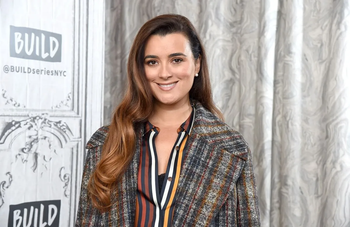 Cote de Pablo posing at AOL's Build series while wearing a long jacket.