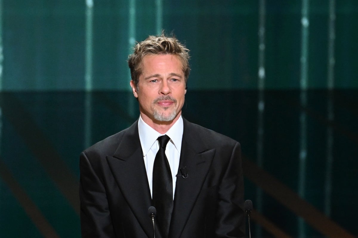 Brad Pitt posing on stage in a suit at the "Honorary César Award".