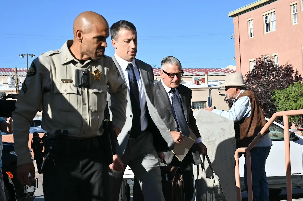 Alec Baldwin and his lawyer walking into court accompanied by a law enforcement officer